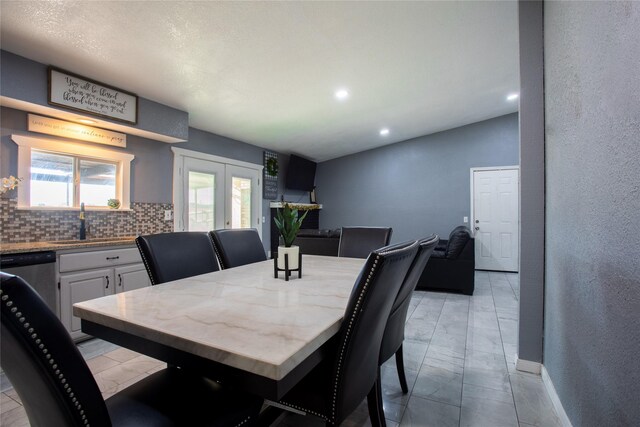 tiled dining area with french doors, lofted ceiling, and sink