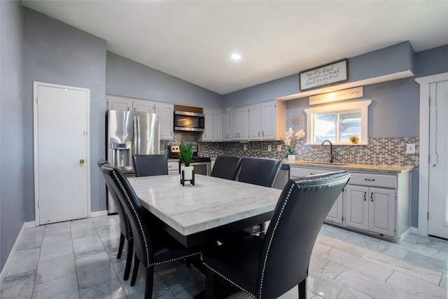 dining room featuring lofted ceiling and sink