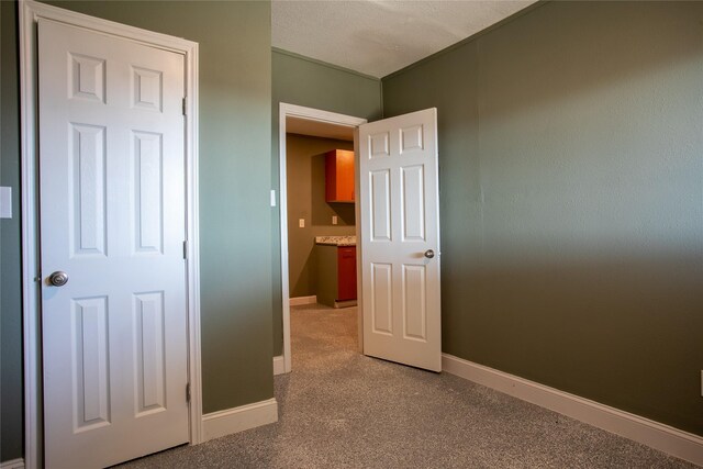 unfurnished bedroom featuring a textured ceiling and light colored carpet