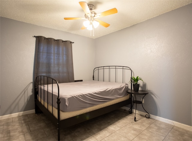 tiled bedroom with ceiling fan and a textured ceiling