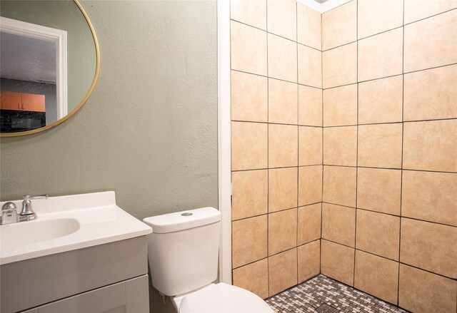 bathroom with vanity, toilet, and a tile shower