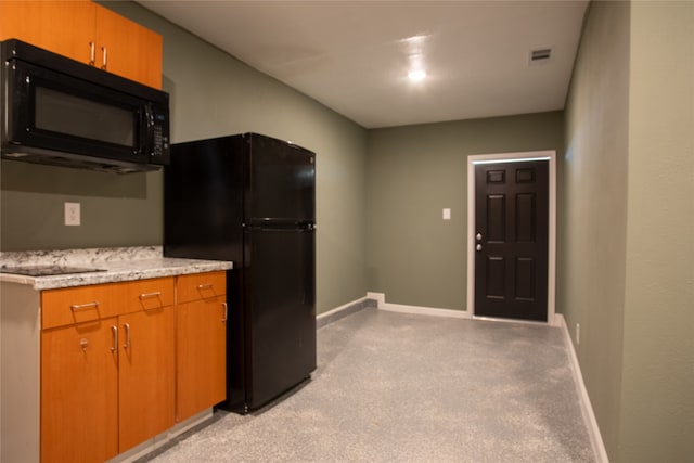 kitchen with black appliances and light colored carpet