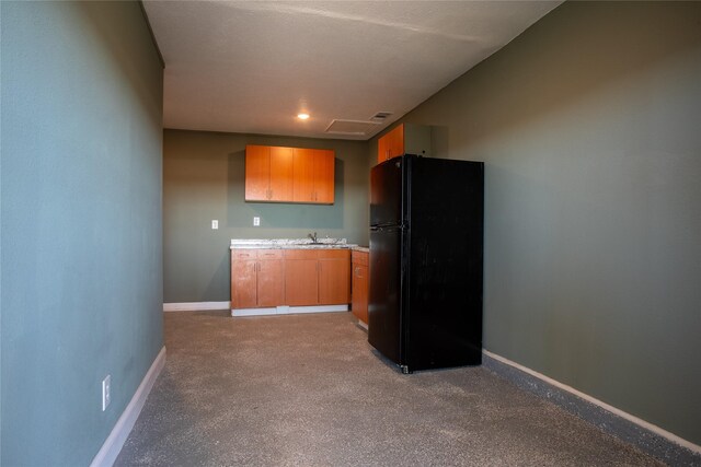 kitchen with black fridge, light colored carpet, and sink