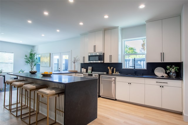 kitchen with a center island, light hardwood / wood-style flooring, white cabinets, and stainless steel appliances