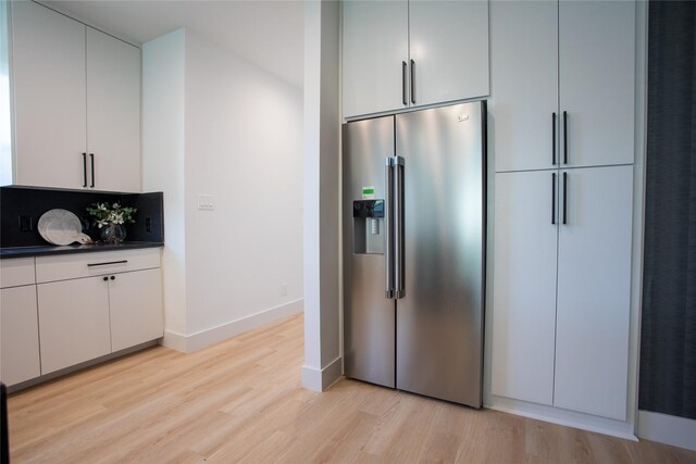 kitchen featuring stainless steel fridge, light hardwood / wood-style flooring, and white cabinets