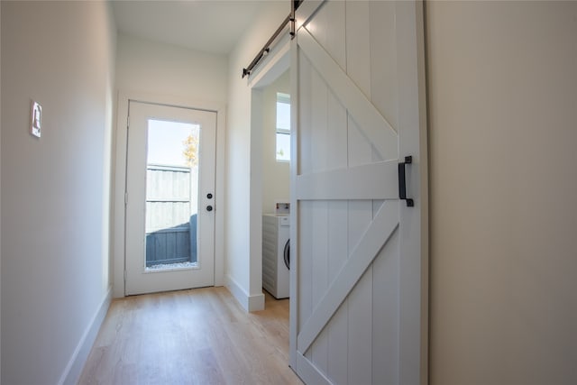 entryway featuring washer / dryer, a barn door, and light wood-type flooring