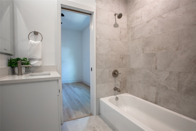 bathroom with hardwood / wood-style flooring, vanity, and tiled shower / bath