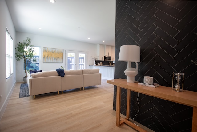 living room with light wood-type flooring, tile walls, and french doors