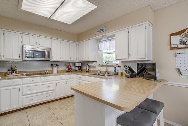 kitchen with white cabinetry, kitchen peninsula, and sink