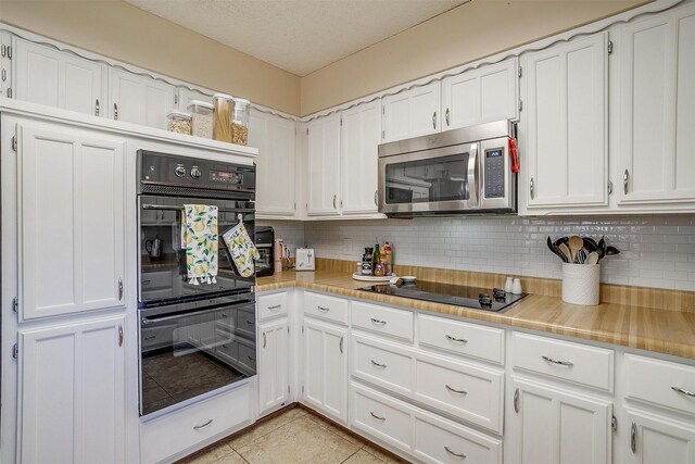 kitchen featuring black appliances, light tile patterned flooring, white cabinets, and tasteful backsplash