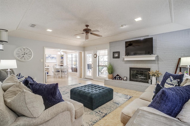 living room with light tile patterned flooring, a textured ceiling, and a brick fireplace