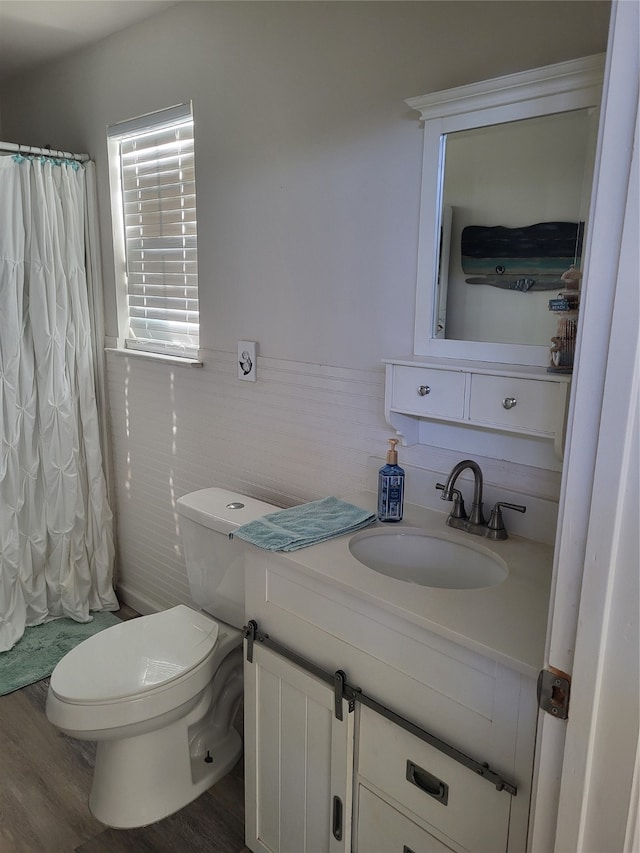 full bathroom featuring hardwood / wood-style floors, vanity, toilet, shower / bathtub combination with curtain, and tile walls