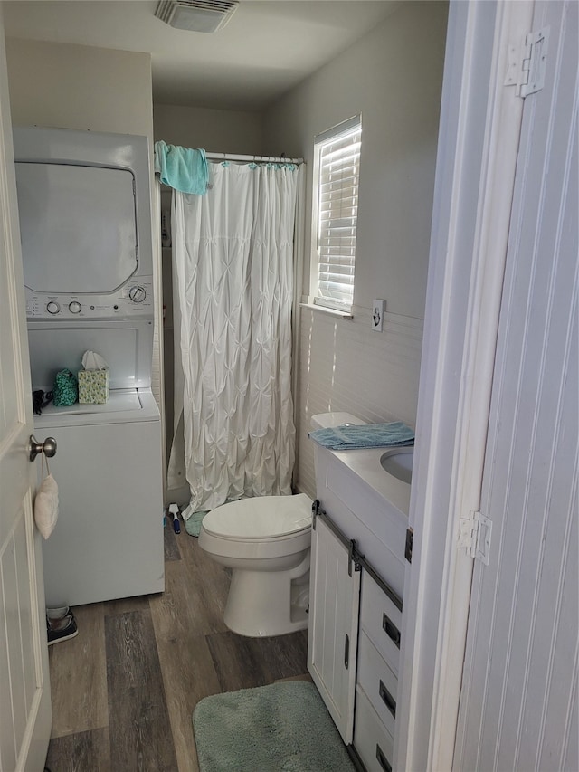 bathroom featuring vanity, toilet, wood-type flooring, and stacked washing maching and dryer