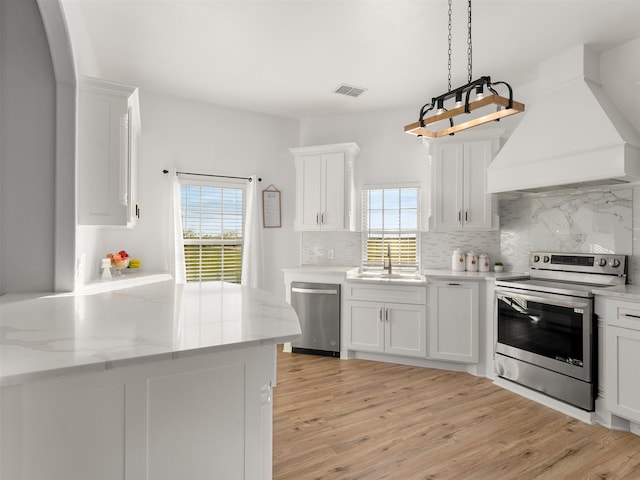 kitchen with white cabinets, premium range hood, and stainless steel appliances