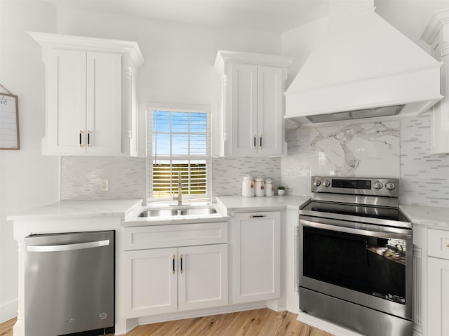 kitchen featuring white cabinets, custom range hood, backsplash, and appliances with stainless steel finishes