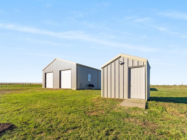 view of outdoor structure with a lawn, a rural view, and a garage