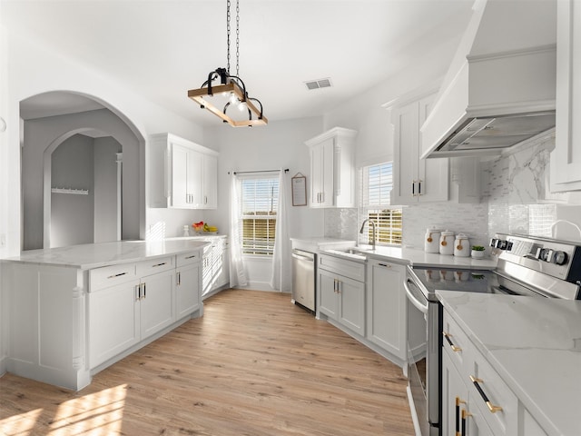 kitchen featuring white cabinets, custom range hood, stainless steel appliances, and light hardwood / wood-style floors