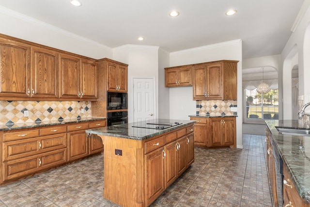 kitchen with dark stone counters, black appliances, sink, decorative backsplash, and a kitchen island