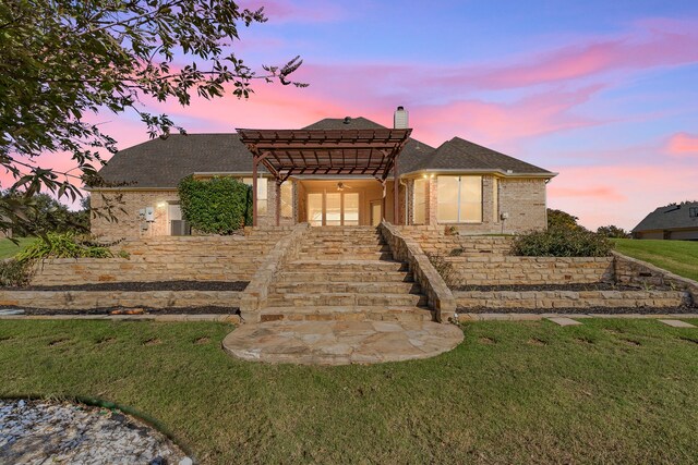 view of front of home featuring a pergola, ceiling fan, and a lawn