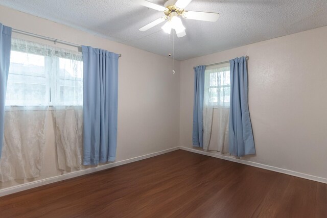 spare room with dark hardwood / wood-style floors, ceiling fan, and a textured ceiling