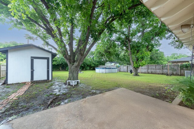 view of yard with a fenced in pool, a patio, a fenced backyard, an outbuilding, and a storage unit