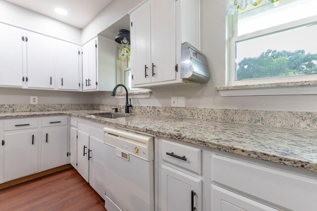 kitchen with wood finished floors, a sink, white cabinetry, light stone countertops, and dishwasher