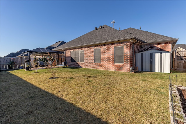 rear view of property featuring a gazebo, a yard, and a storage shed