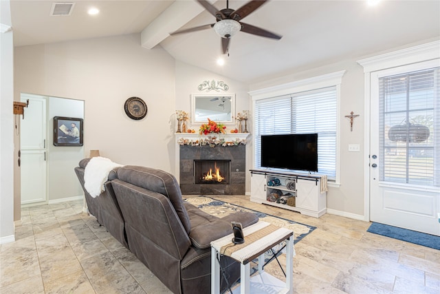 living room with a tiled fireplace, ceiling fan, plenty of natural light, and lofted ceiling with beams