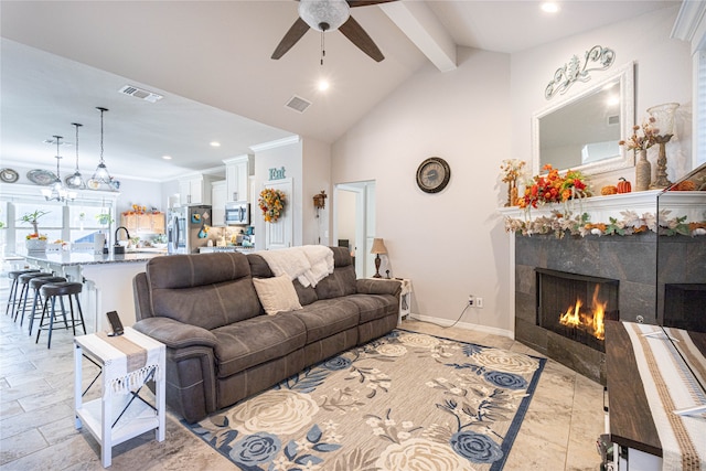 living room with ceiling fan, sink, vaulted ceiling with beams, a high end fireplace, and crown molding