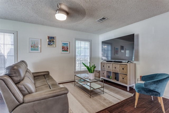 living room featuring wood-type flooring, a textured ceiling, and ceiling fan