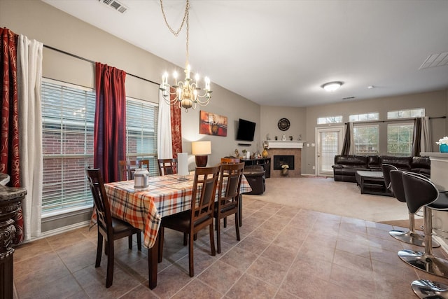 dining area featuring a fireplace, carpet, and a chandelier