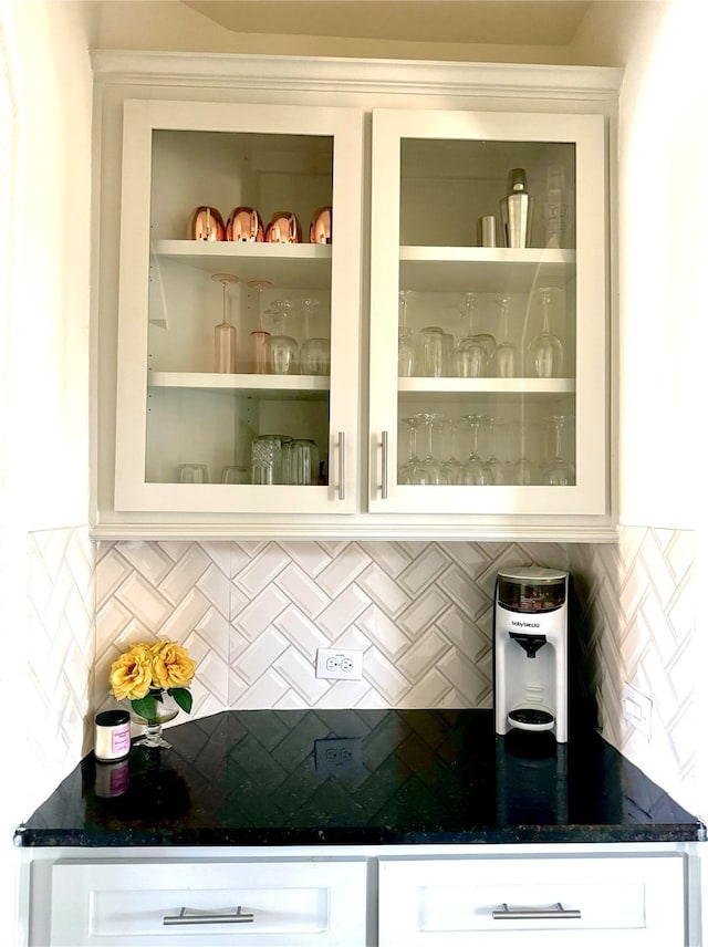 bar featuring white cabinets, decorative backsplash, and dark stone counters