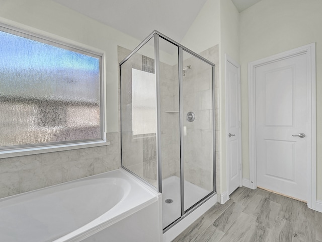 bathroom featuring shower with separate bathtub, vaulted ceiling, and plenty of natural light