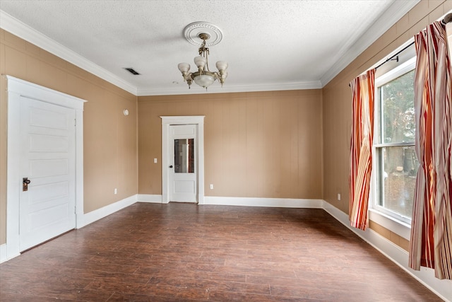 spare room featuring dark hardwood / wood-style flooring, ornamental molding, a textured ceiling, and an inviting chandelier