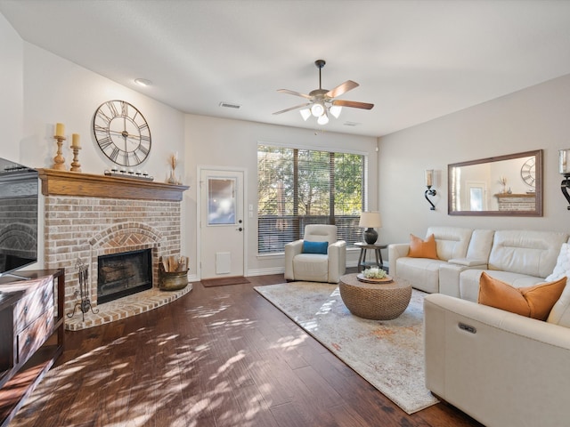 living room featuring ceiling fan, dark hardwood / wood-style flooring, and a brick fireplace