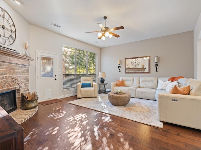 living room featuring dark hardwood / wood-style flooring, a brick fireplace, and ceiling fan