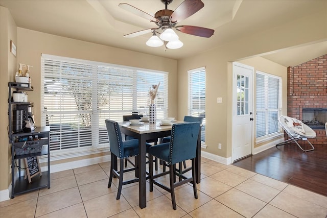 dining room featuring a fireplace, light hardwood / wood-style floors, and ceiling fan