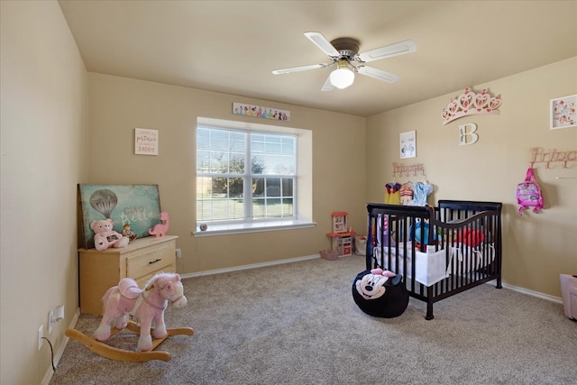 bedroom with light colored carpet, a nursery area, and ceiling fan