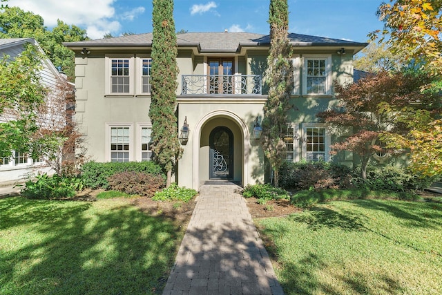 view of front of property with a balcony and a front lawn