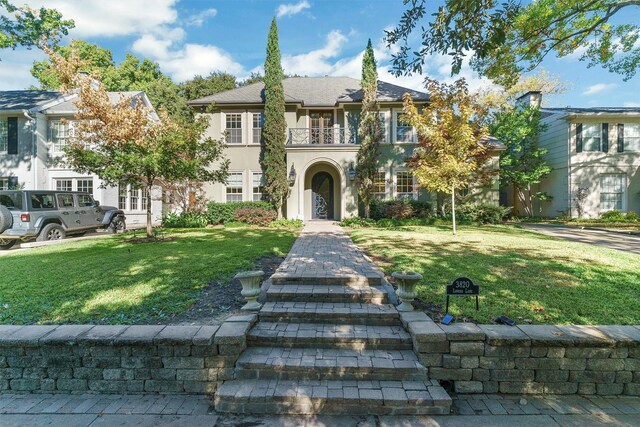 view of front facade featuring a balcony and a front lawn