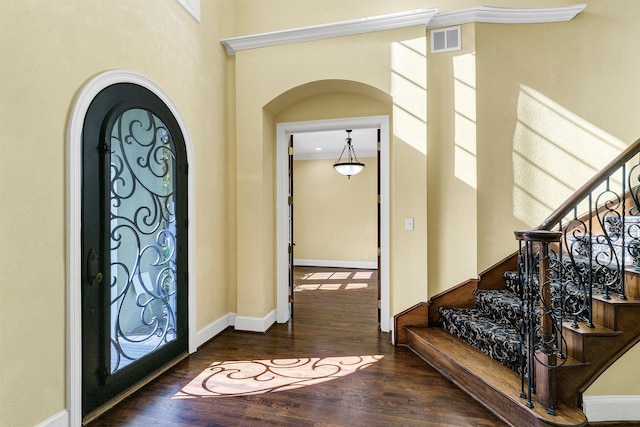 entryway with ornamental molding and dark wood-type flooring