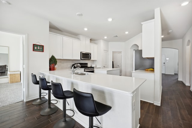 kitchen with kitchen peninsula, dark hardwood / wood-style flooring, white cabinets, and appliances with stainless steel finishes