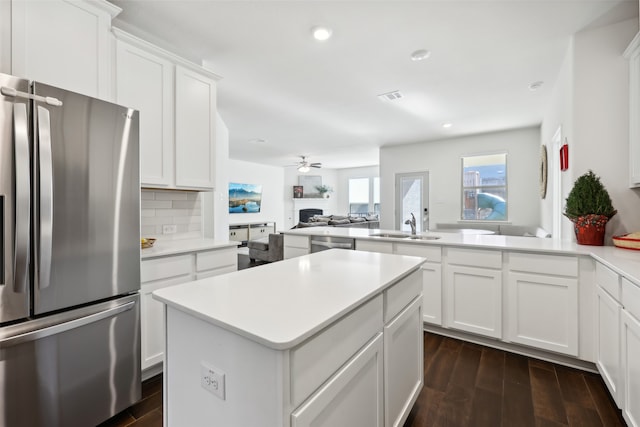 kitchen with kitchen peninsula, dark hardwood / wood-style flooring, white cabinets, and stainless steel appliances