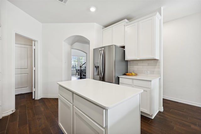 kitchen featuring decorative backsplash, stainless steel fridge, a kitchen island, dark hardwood / wood-style floors, and white cabinetry