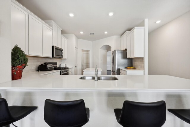 kitchen featuring sink, white cabinets, a kitchen breakfast bar, kitchen peninsula, and stainless steel appliances