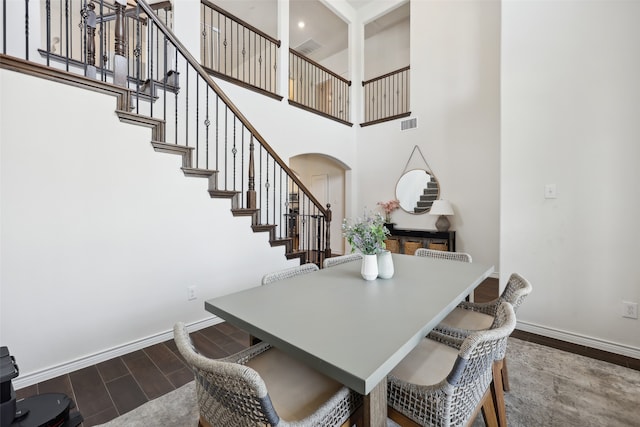 dining room with hardwood / wood-style floors and a towering ceiling