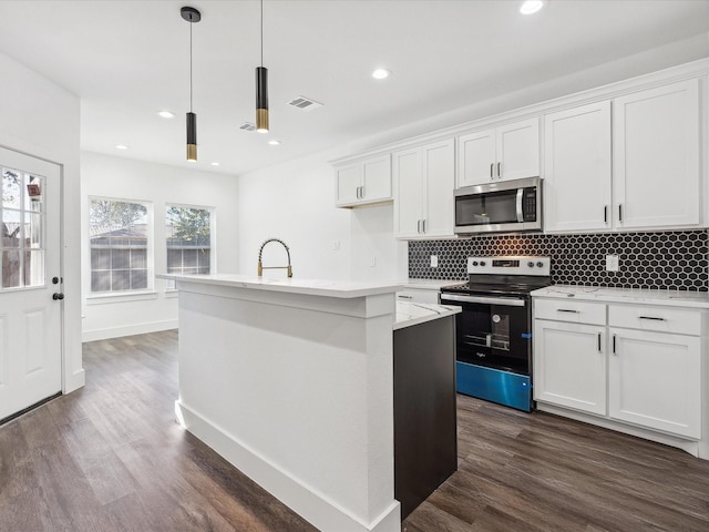 kitchen with appliances with stainless steel finishes, decorative light fixtures, dark hardwood / wood-style floors, white cabinetry, and an island with sink