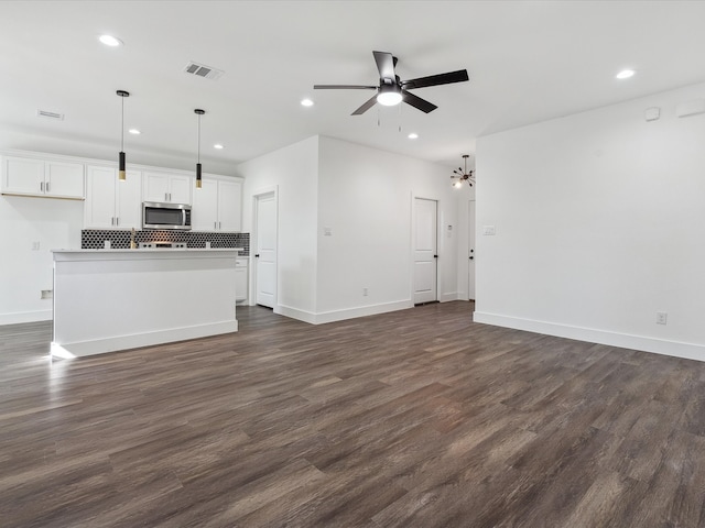 unfurnished living room featuring dark hardwood / wood-style floors and ceiling fan with notable chandelier