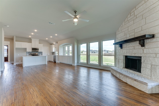 unfurnished living room featuring a stone fireplace, ceiling fan, lofted ceiling, and hardwood / wood-style flooring