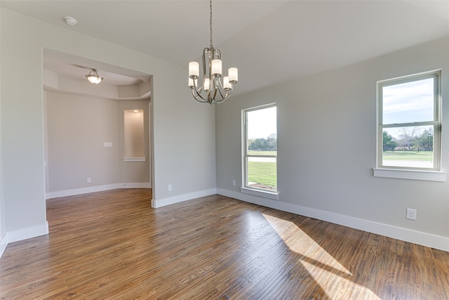 spare room featuring wood-type flooring and a chandelier